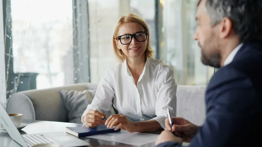 Insurance advisor smiling while reviewing coverage documents with a client across a table