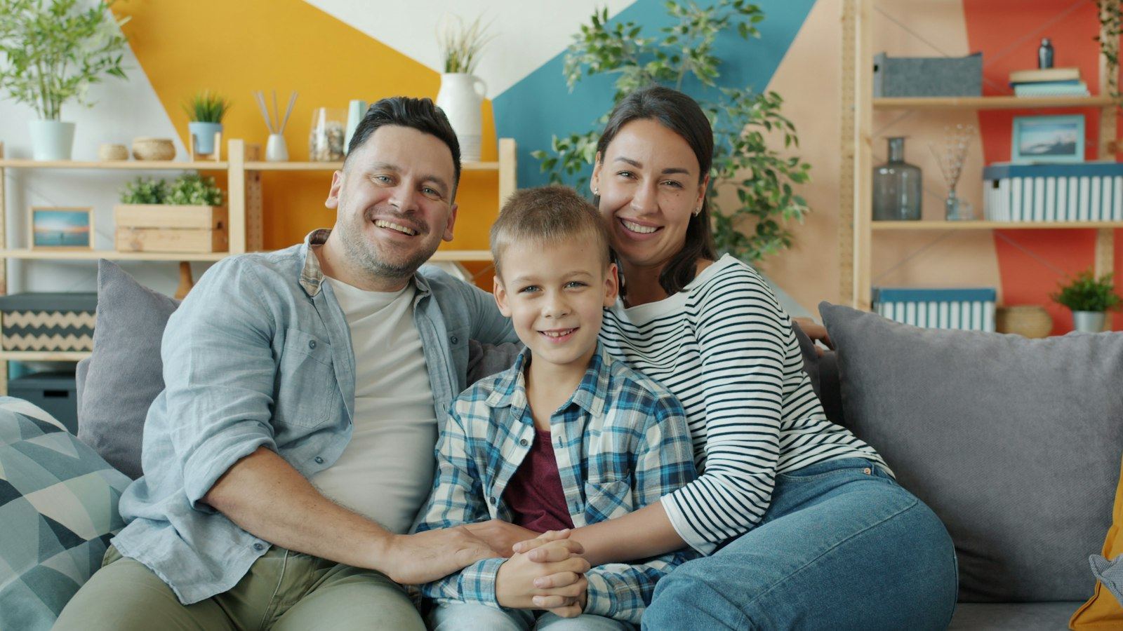 Parents sitting with their son on a sofa at home, smiling together